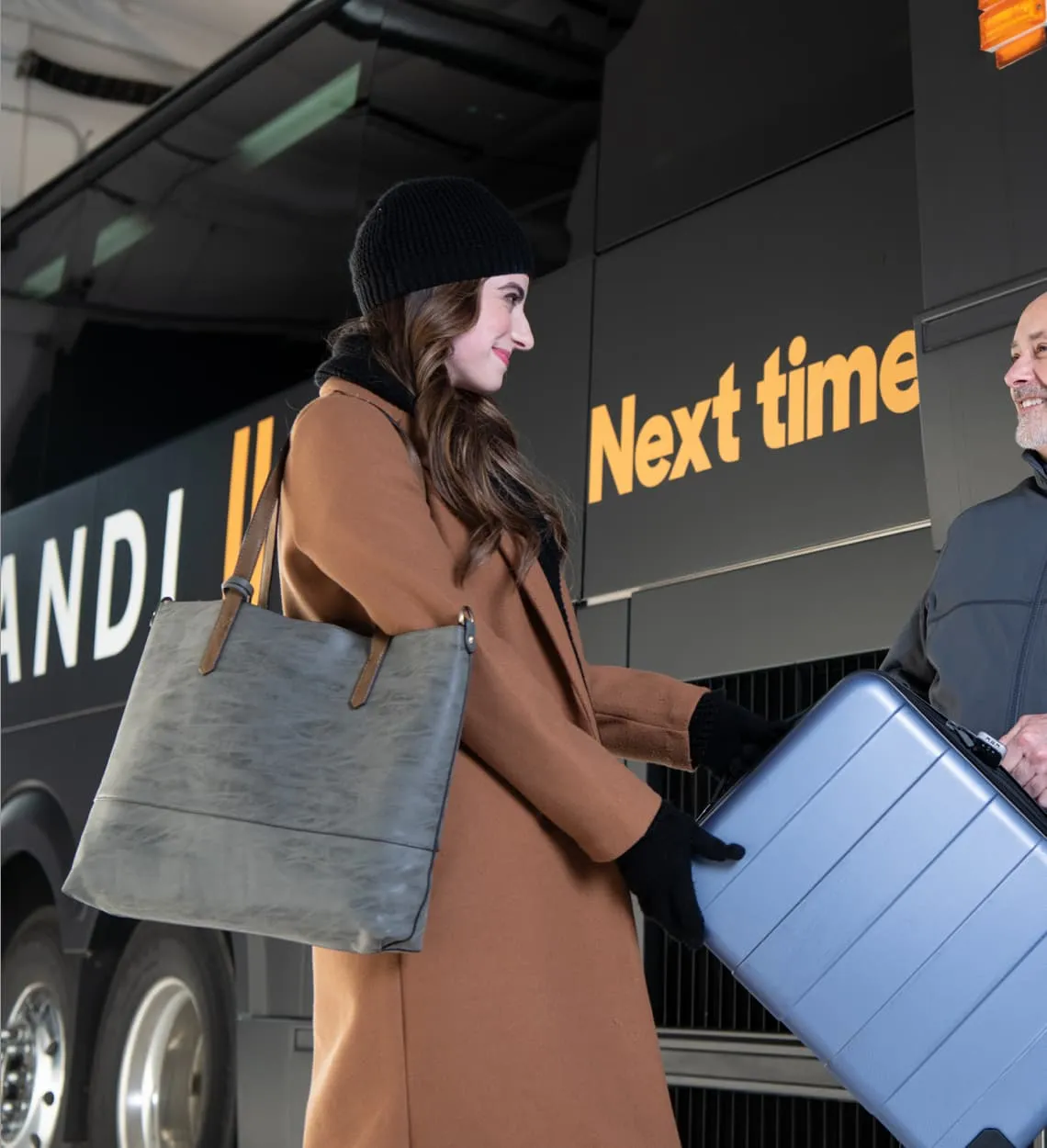 A driver taking a passenger's suitcase beside a Landline coach.