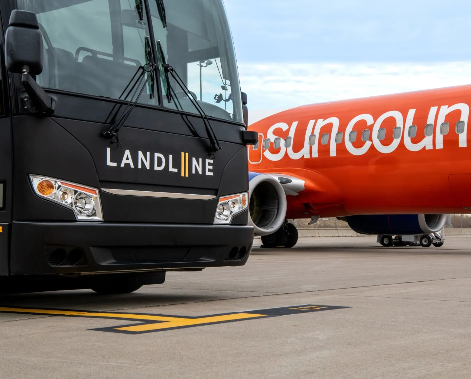 A Landline coach parked nose to nose with a Sun Country jet on the ramp.