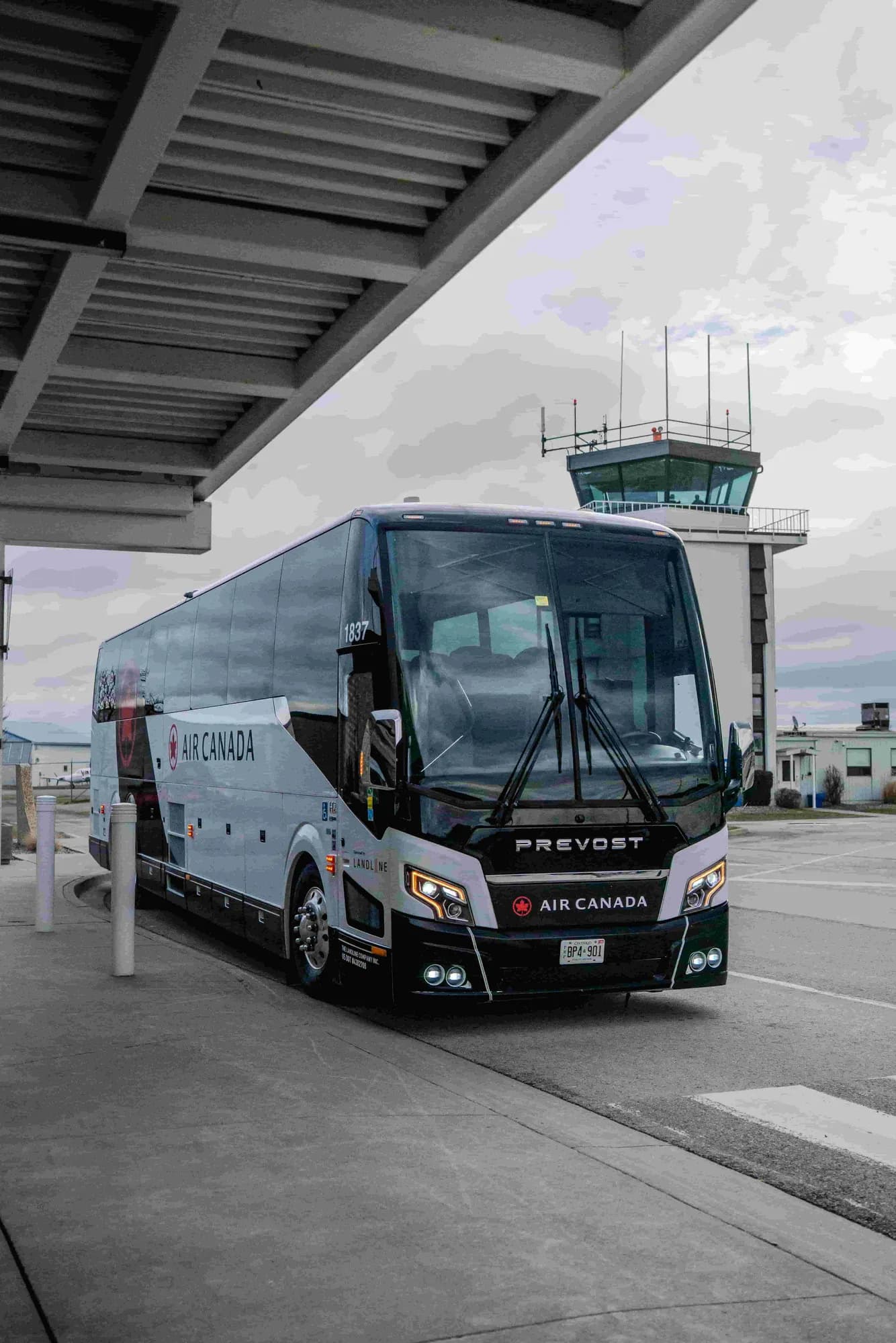 A Landline motorcoach at an airport terminal curb.