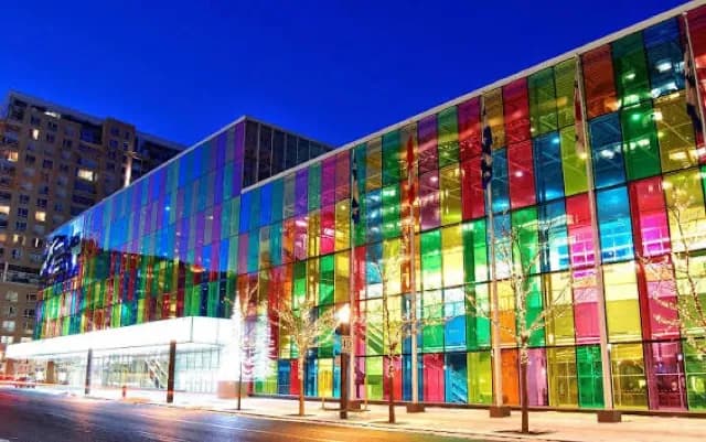 The coloured glass facade of the Palais des congrès de Montréal at dusk.