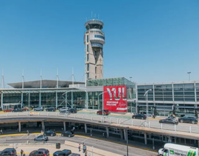 The control tower and departures curb at Montréal-Trudeau International Airport, with the red YUL sign on the terminal.